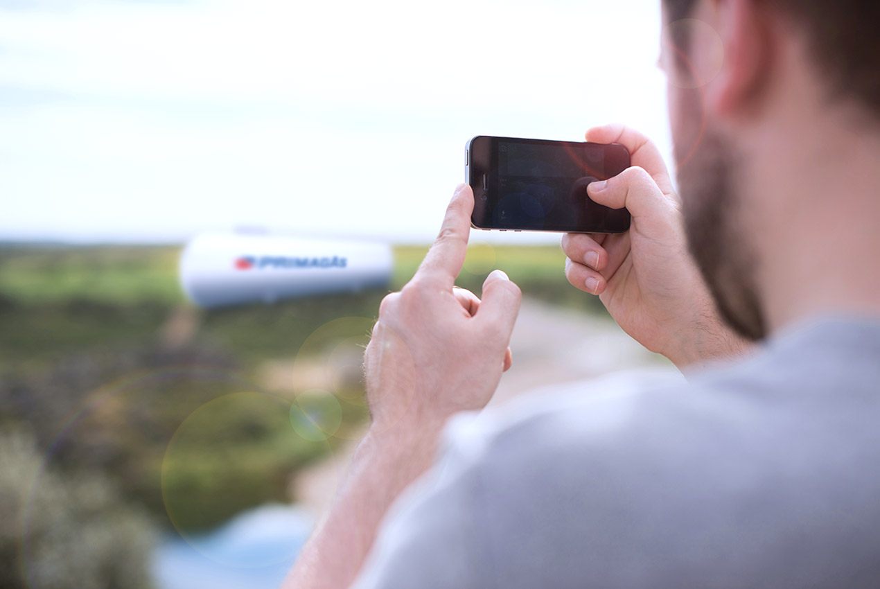 PRIMAGAS Fotodokumentation, Mann mit Handy fotografiert einen Flüssiggas-Tank